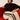 Woman sitting on a red couch wearing a striped sweater and beige pants with black stripes.