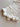 Mila Pointelle Tie Romper Snow knitted in a signature pointelle design featuring snap openings for easy nappy changes and leg frills shown in a close up view.
