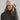 Woman wearing a beige knit beanie with a pom-pom on a plain background