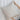 Person holding a beige pillow against a white curtain background