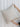Person holding a beige pillow against a white curtain background