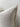 Close-up of a beige pillow with frayed edges on a neutral background