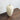 Angled view of the tall, off-white porcelain narrow neck vase resting on a dark wooden surface.