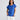 Close-up front view of a model wearing the Percy Top in Cobalt paired with white trousers.