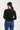 Person wearing a black sweater and blue jeans on a white background