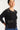 Woman wearing a black cardigan with decorative buttons on a white background