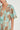 Close-up detail of the Premier Dress in mint kgari showing the V-neckline, button bodice, and flutter sleeves.