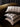 Studio display of stacked reversible stripe 30x50cm linen cushions on an armchair, showcasing the Olive, Black, and Bronze color variants in their geometric patterns.