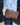 Raffia clutch with crossbody chain in chocolate brown worn as a crossbody bag with a gold chain strap.