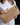 Raffia clutch with crossbody chain in natural raffia featuring a round vintage-style gold clasp and structured design.