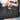 Raffia Clutch with gold chain in black featuring a snap handle closure shown held by the handle.