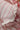 Raised Stripe Tie Romper Sweetpea knitted in a raised sweetpea stripe on a soft snow base featuring leg frills and snap openings shown in a close up view.