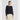 Woman wearing a navy textured sweater with beige pants on a white background