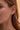 Lifestyle close-up view of a model wearing the gold-plated Reina Hoops featuring a stack of multi-coloured gemstones.