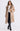Woman wearing a faux fur beige coat with fur collar on a white background