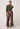 Woman wearing a green sweater and patterned pants on a white background