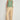 Full length view of a model wearing the Sense Vest in apple green paired with neutral trousers, showcasing a relaxed sleeveless fit and utilitarian character.