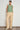 Full length view of a model wearing the Sense Vest in apple green paired with neutral trousers, showcasing a relaxed sleeveless fit and utilitarian character.
