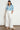 Sienne Top in Song Bird blue floral print front view, featuring a 100% cotton relaxed fit, V-neckline with button-through design, and short raglan sleeves with gathered details paired with white trousers.