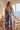 Tia Valencia Dress crafted from 100% hemp featuring a vibrant blue and red floral print shown in an outdoor lifestyle view.