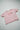 Flat lay of the pink reverse side of the organic cotton traveller tee featuring the Too jet lagged for kindy graphic.
