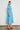 Valour Dress Lagoon shown from the side profile highlighting the feminine curved hem and relaxed midi fit.